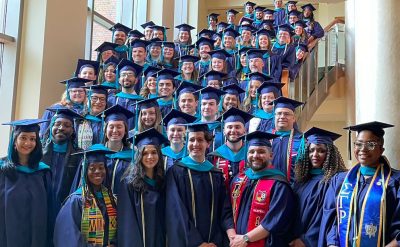A group photo of students in caps and gowns at graduation.