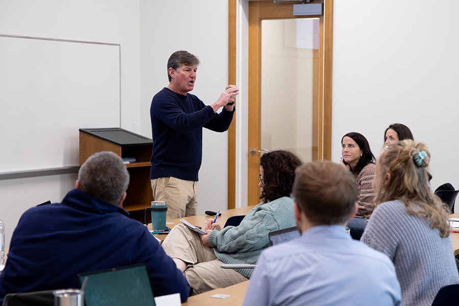 A professor leads a lecture in a small seminar class. 
