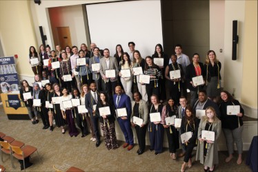 2024 Pi Alpha Alpha Inductees holding their certificates and wearing graduation cords.