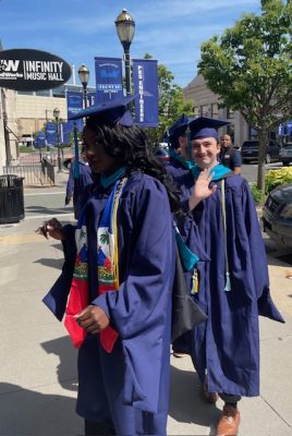 a man waves from a procession line at graduation festivities